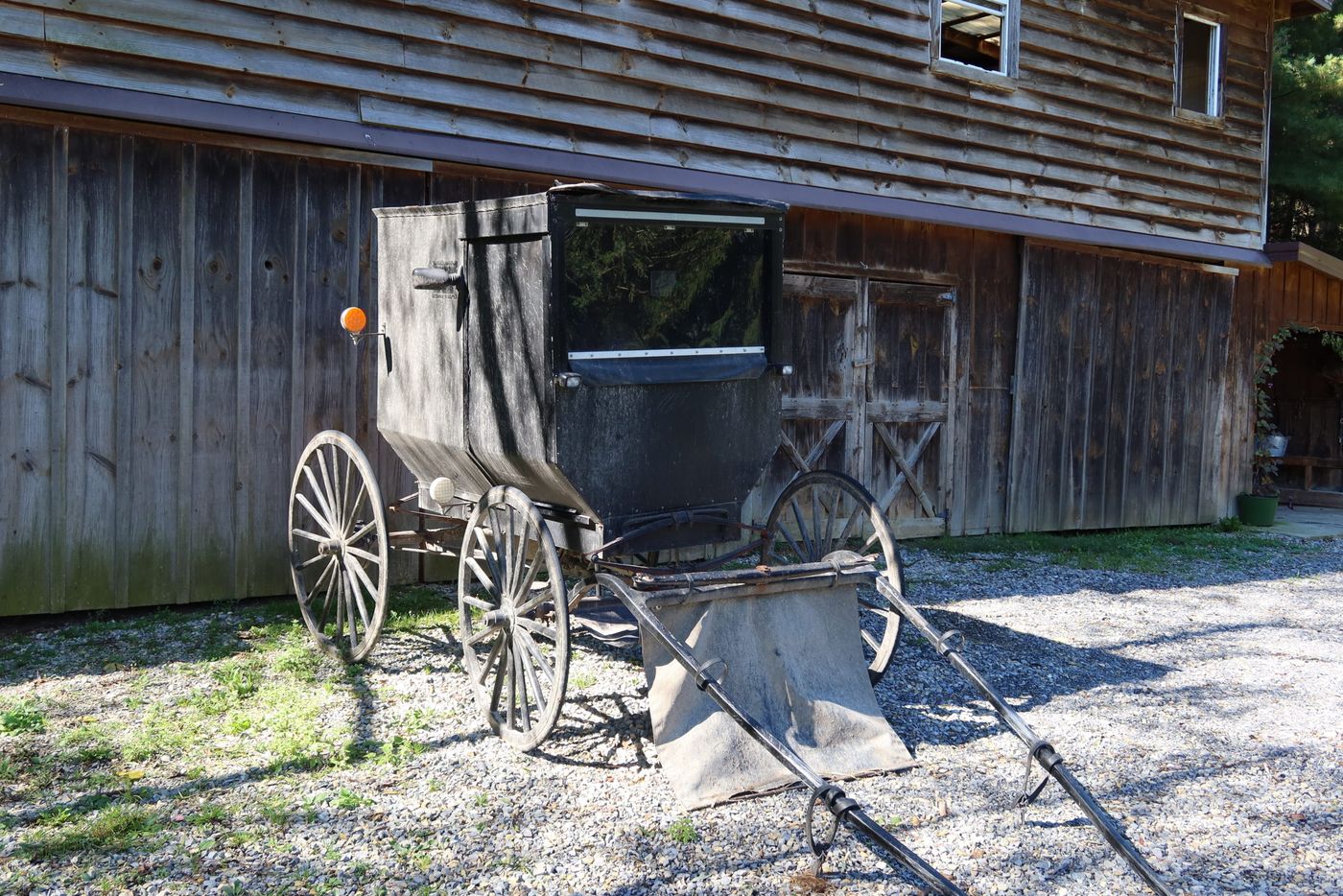 Buggy parked beside a weathered barn